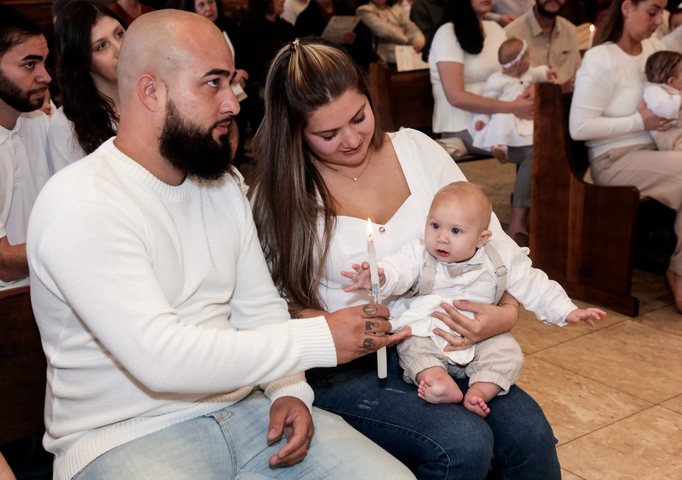 Fotografia de batizado em Piracicaba — pai com a vela do batismo ao lado da família