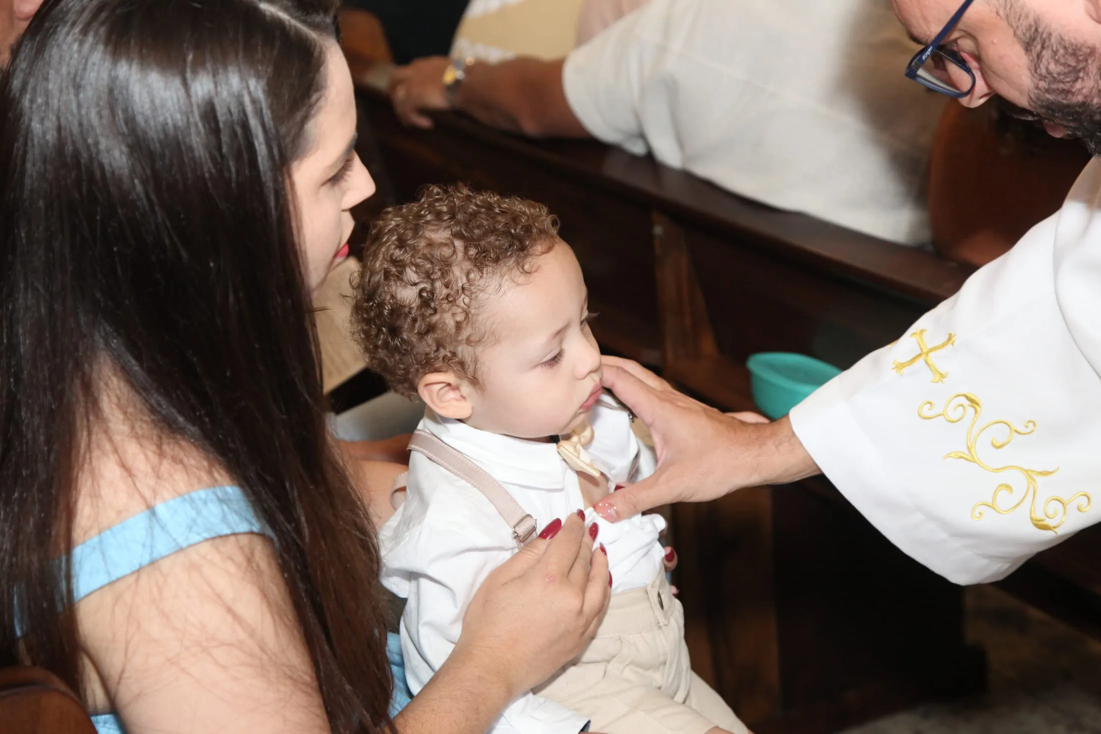 Batismo em Piracicaba — padre abençoando a cabeça da criança no colo da mãe